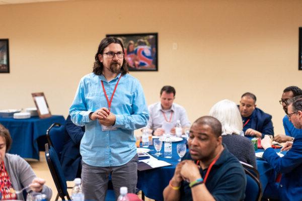 全球最大的博彩平台教授Bryan Pearce-Gonzales博士.D. 站着，穿着一件蓝色的衬衫.